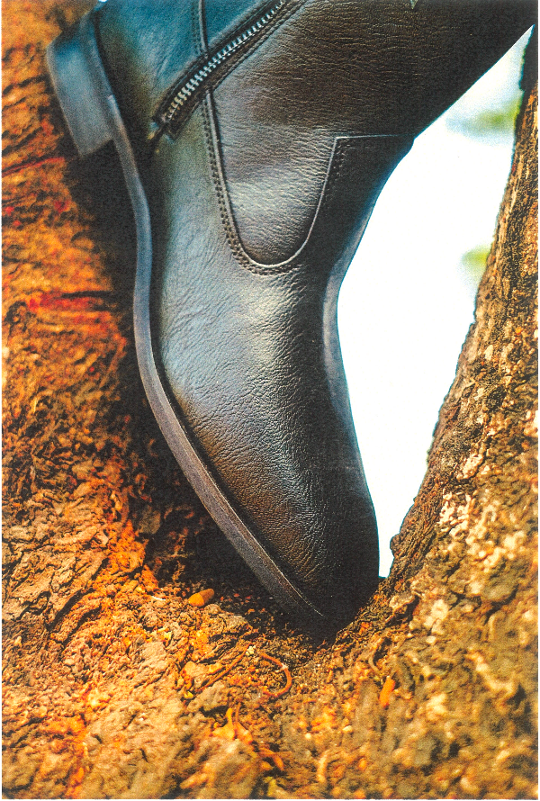 Black leather shoe with a zipper on a textured surface